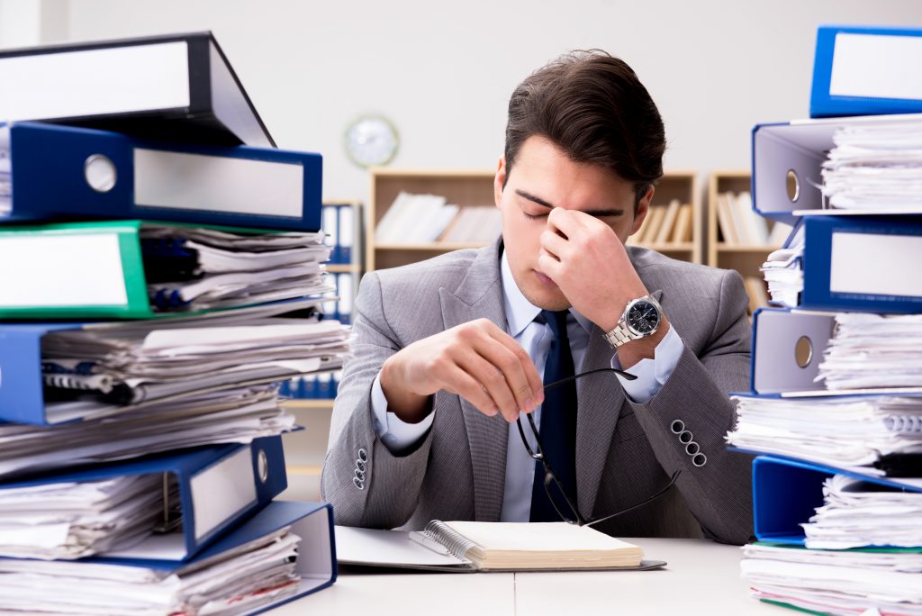 Worker sat at desk surrounded with folders of documents